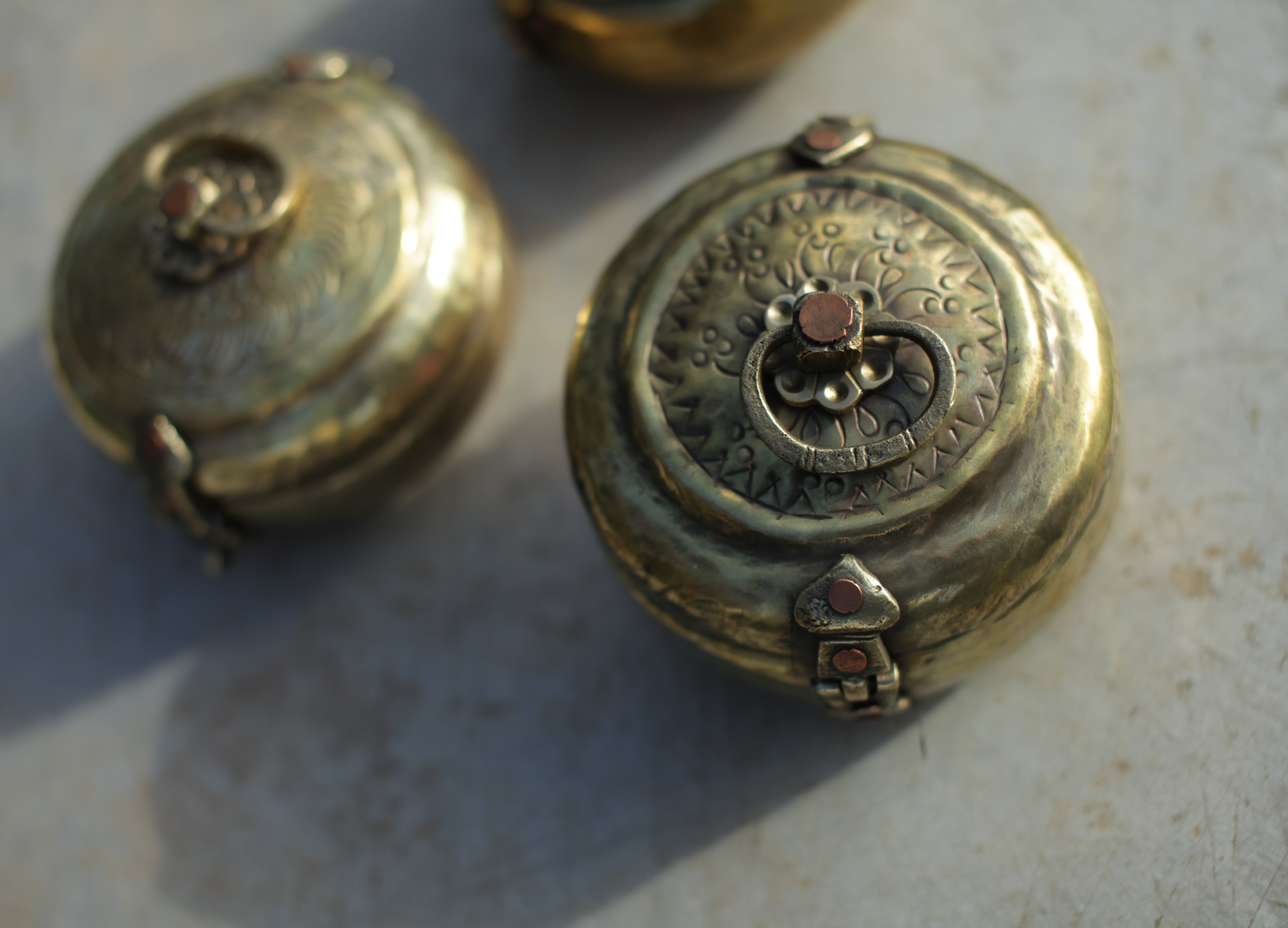 Two ornate brass lockets on a textured surface