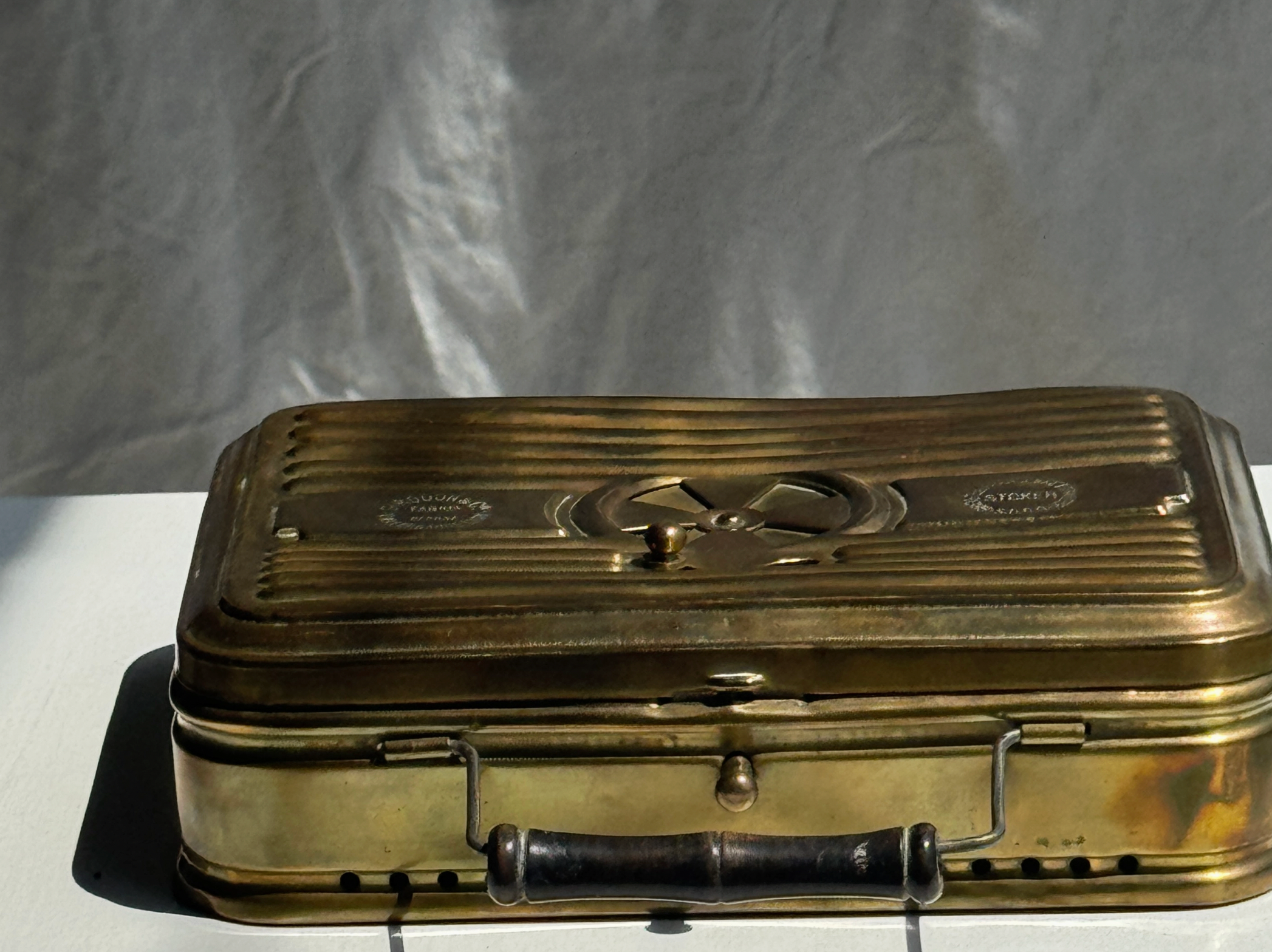 Vintage brass suitcase on a white surface with a gray background
