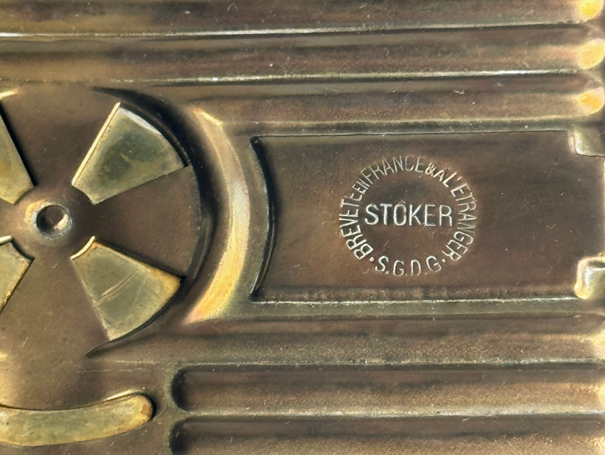 Close-up of a brass or bronze object with 'Stoker' branding and engraved text.