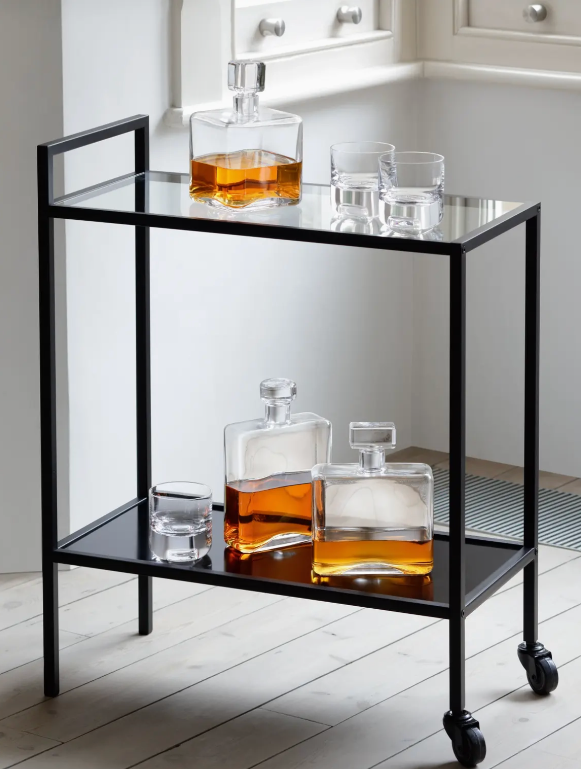 Bar cart with whiskey decanters on a light wooden floor