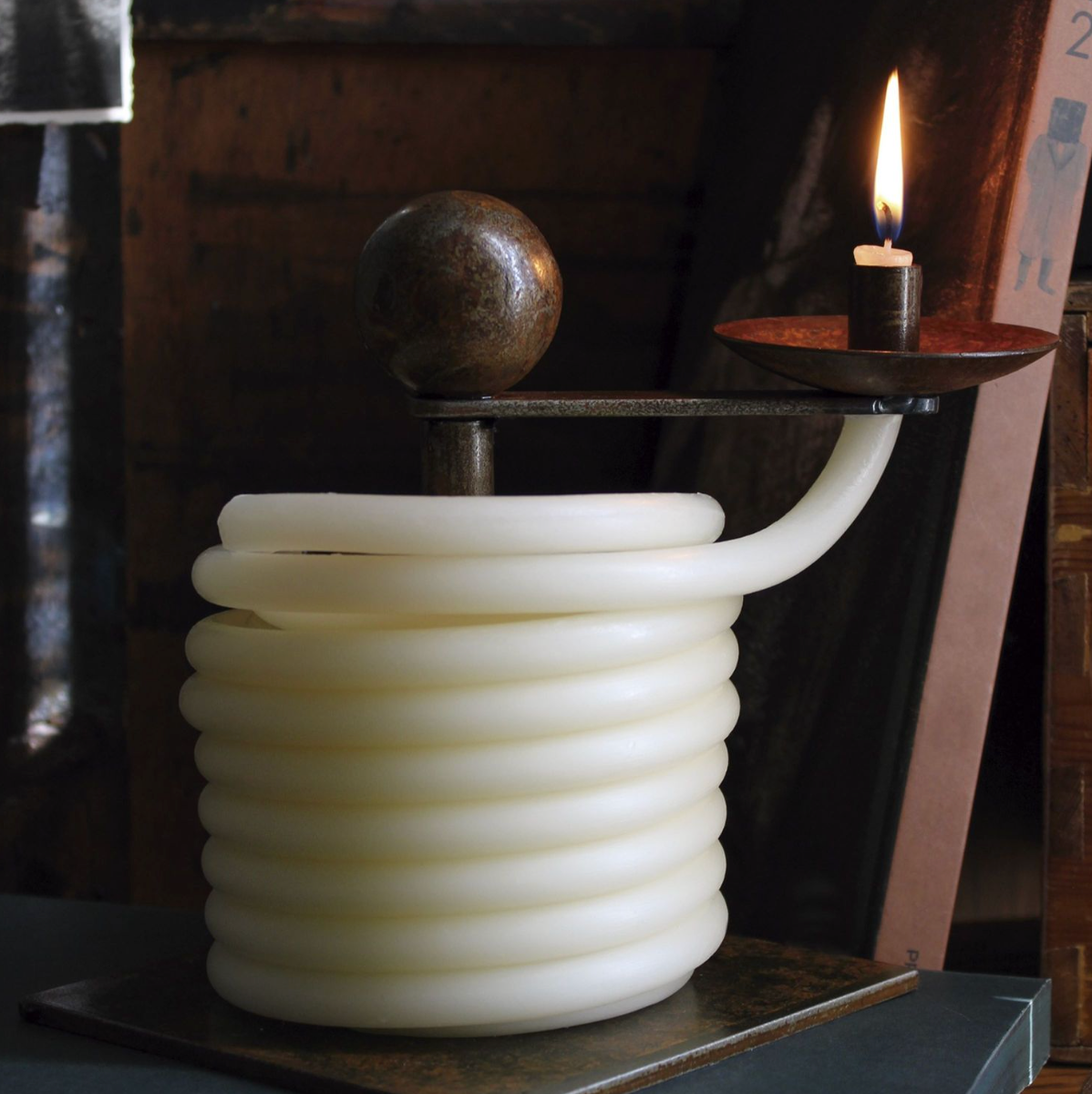 White coiled hose with a lit candle on top, set against a dark background.