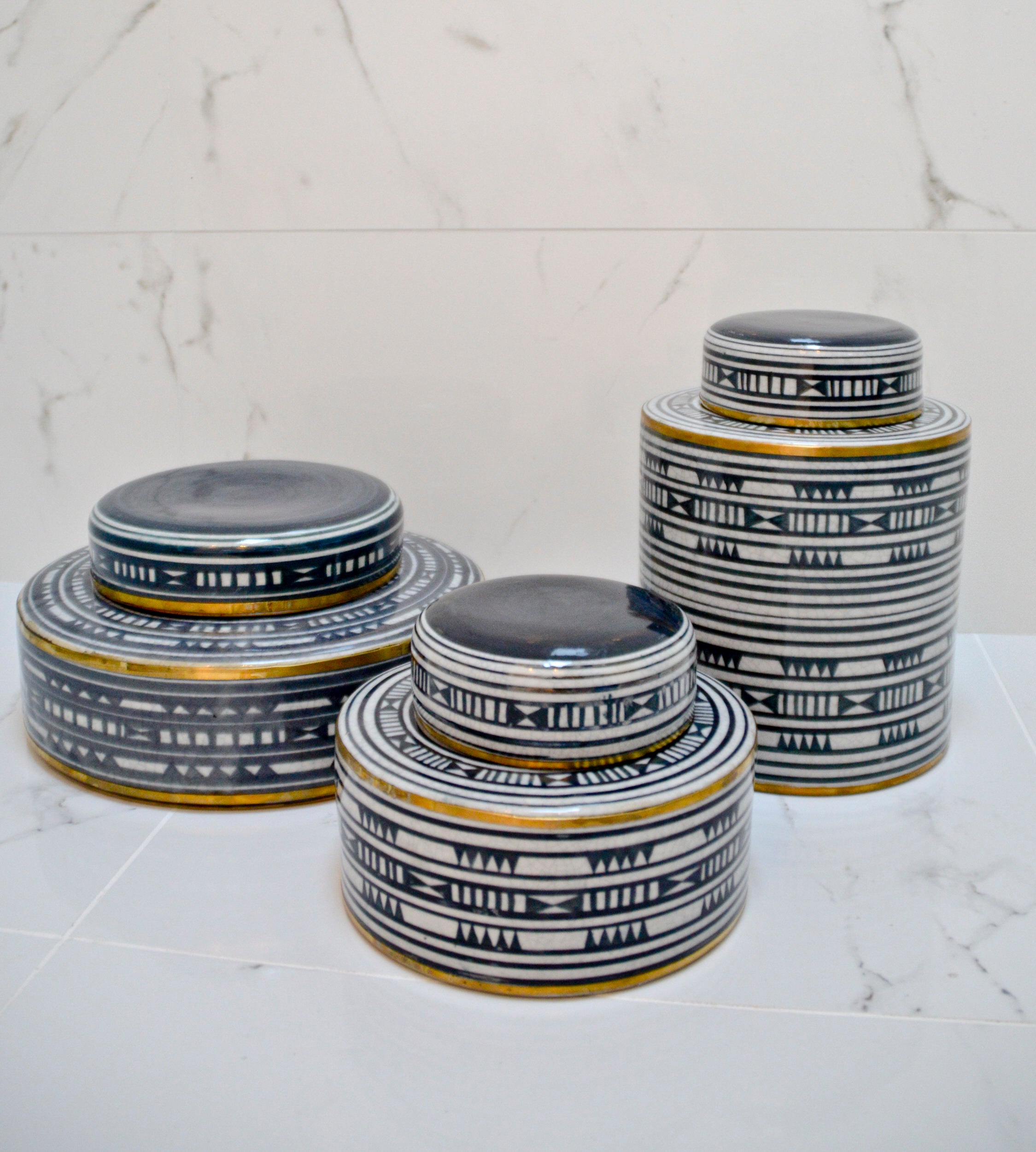 Set of four ceramic jars with black and white patterns on a marble surface