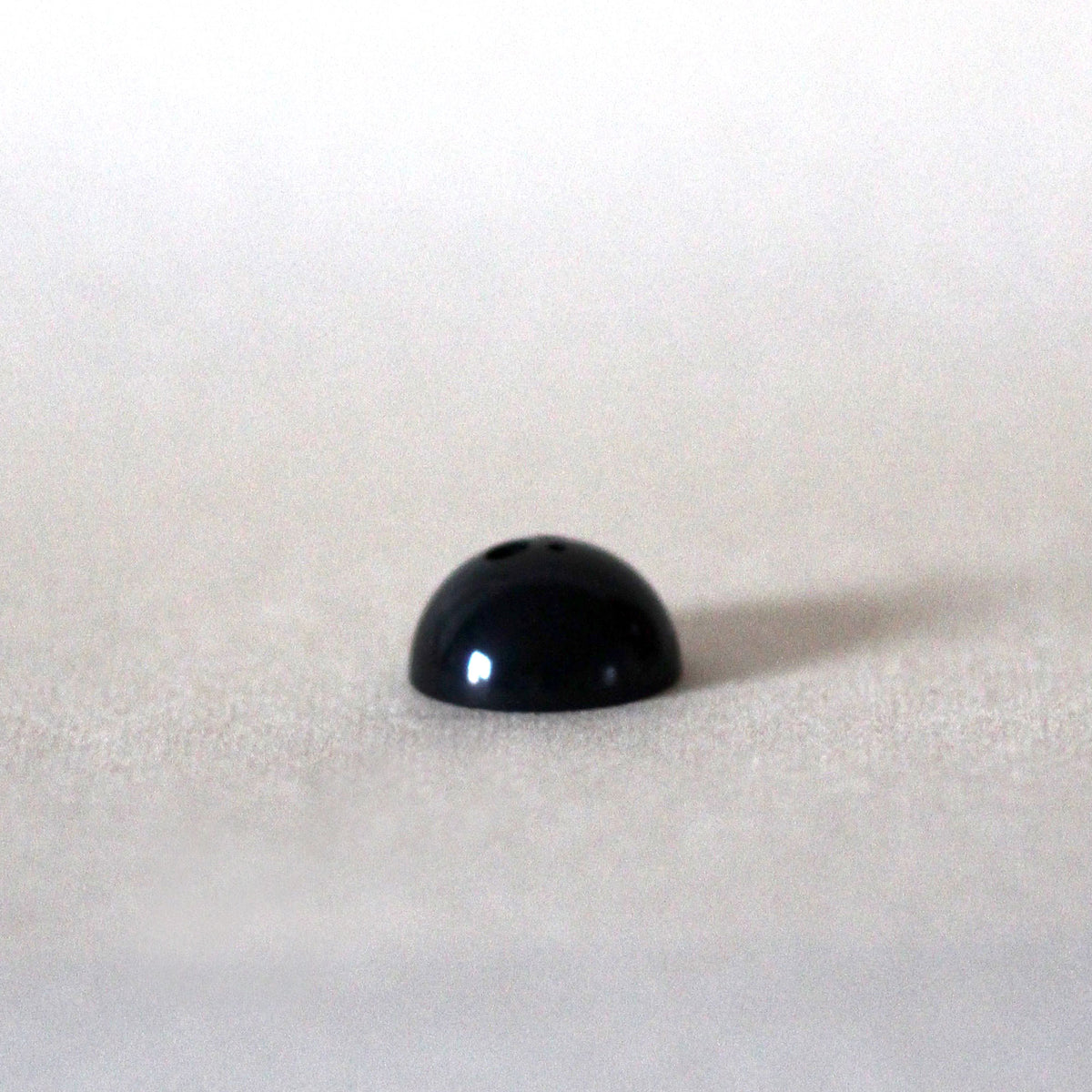 Black dome-shaped object on a white background