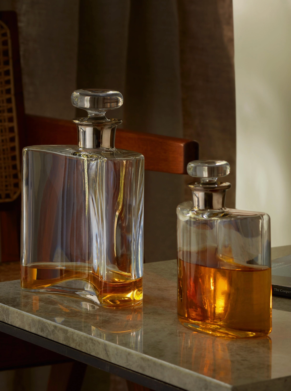 Two glass decanters with liquid on a marble surface