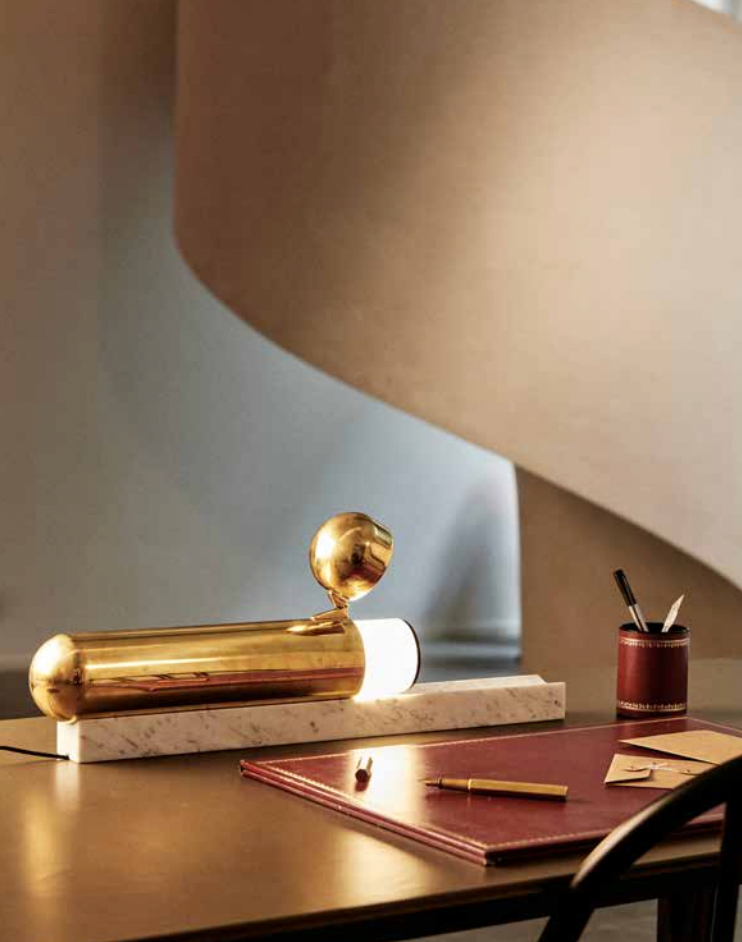 Gold desk lamp on a wooden desk with a neutral background