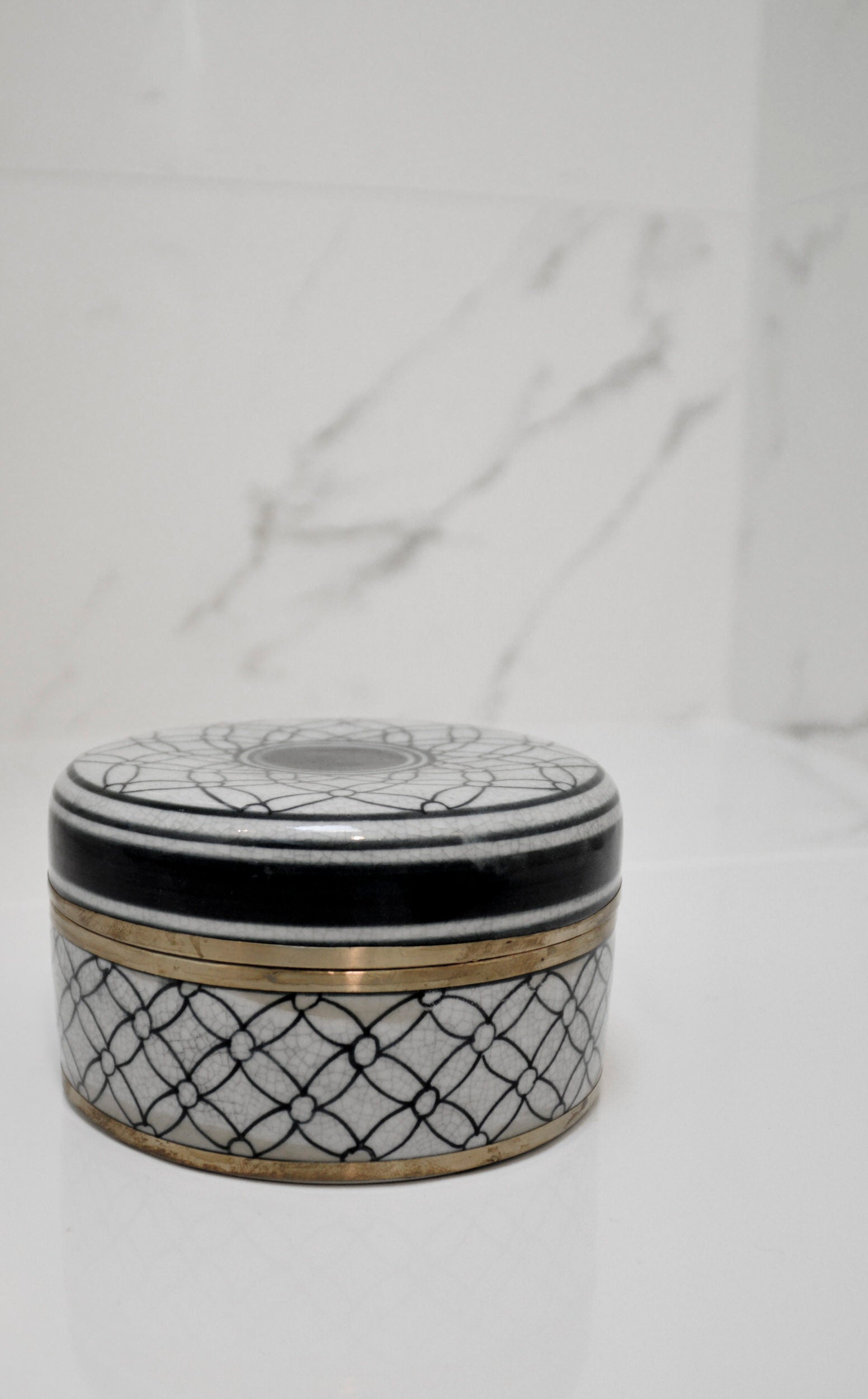 Decorative ceramic jar with black and white pattern on a marble surface