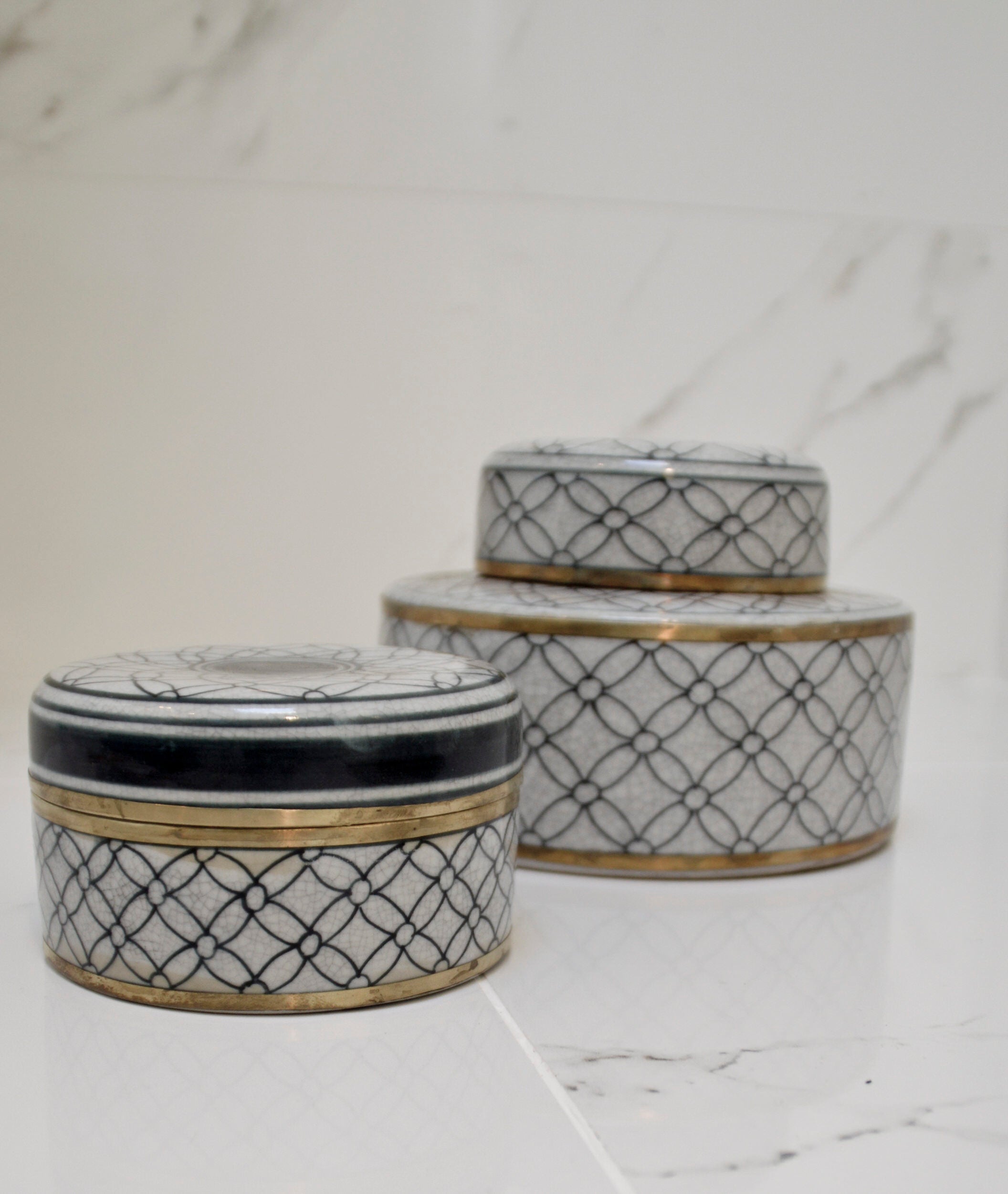 Three decorative ceramic containers with geometric patterns on a marble surface