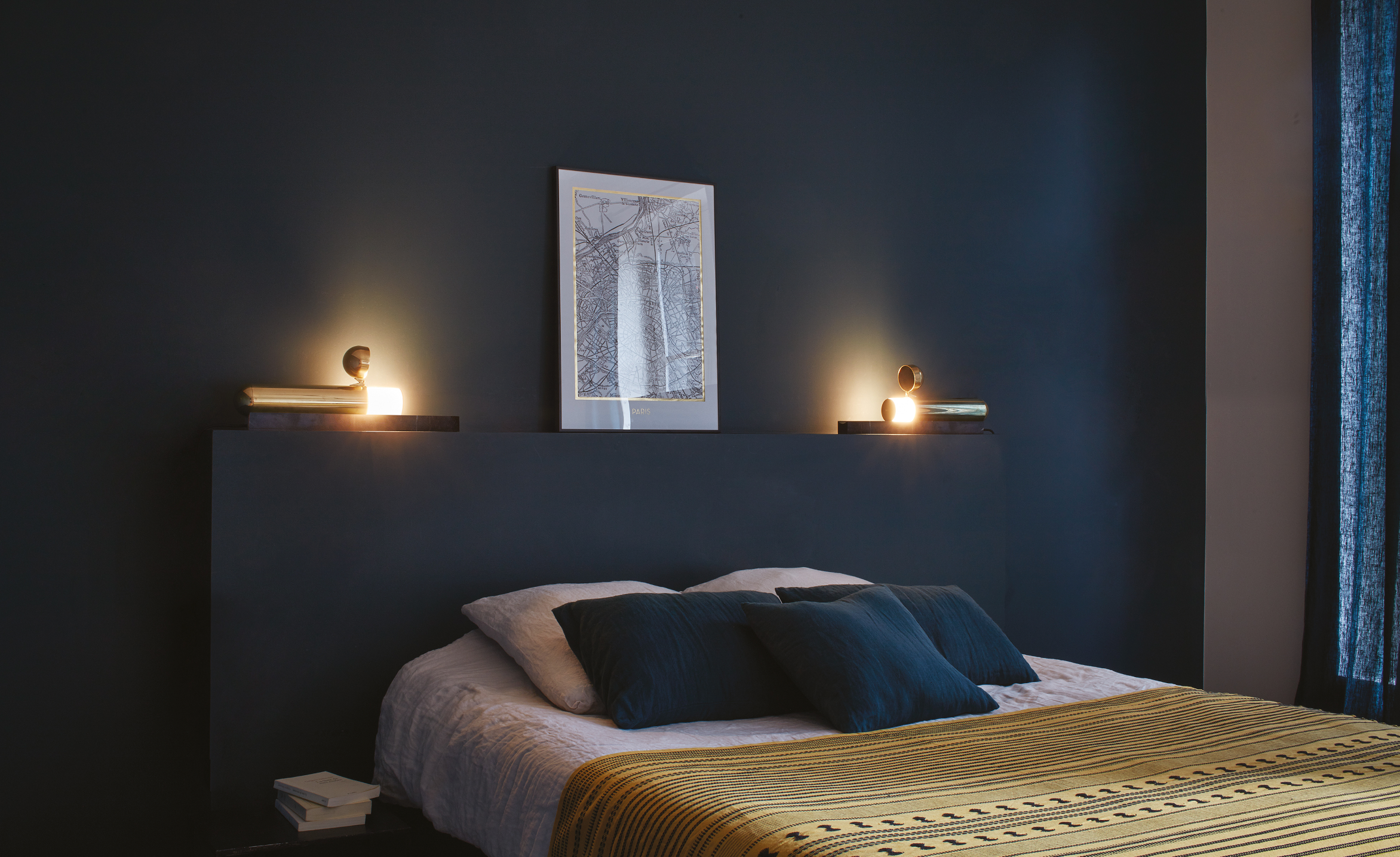 Dark bedroom with a bed, wall art, and candles creating a cozy atmosphere.