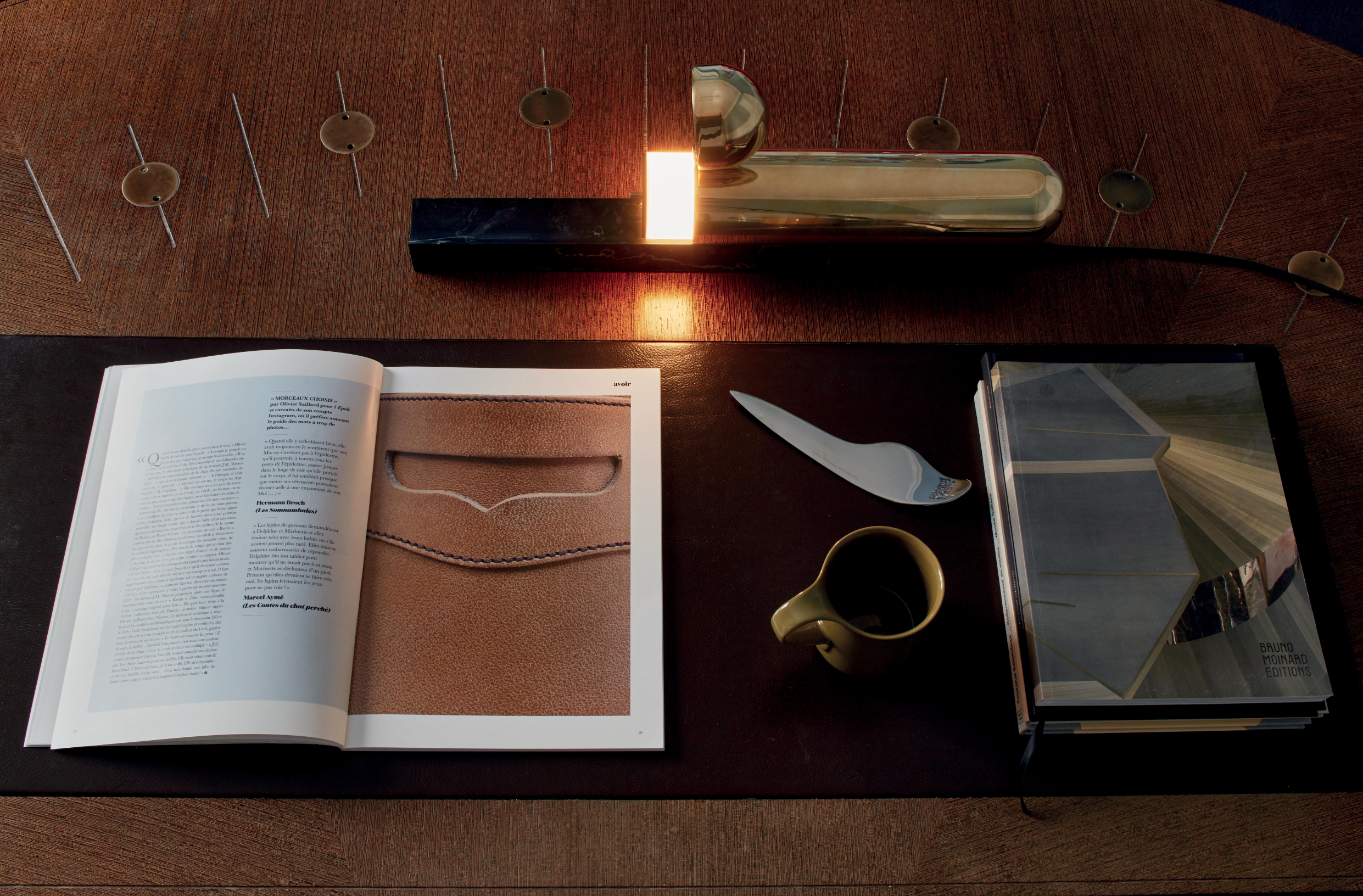 Open book with a leather-bound product on a wooden surface