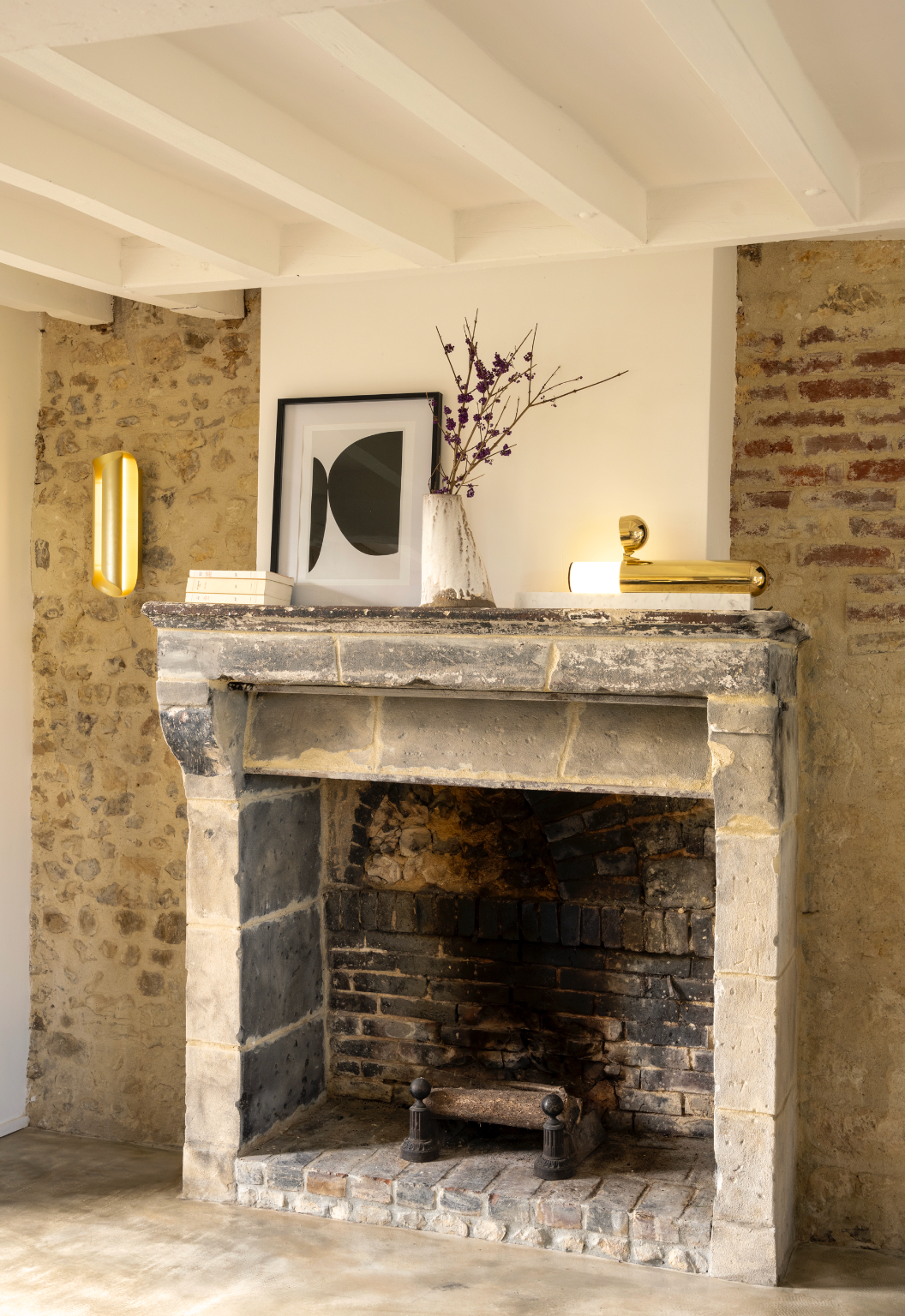 Stone fireplace with decorative items in a room with exposed brick walls.