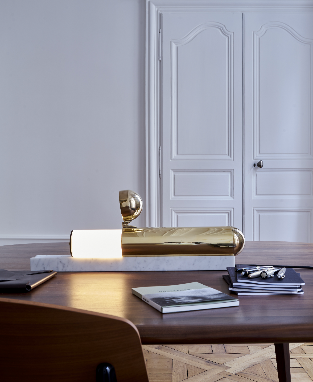 Gold desk lamp on a wooden desk with a neutral background