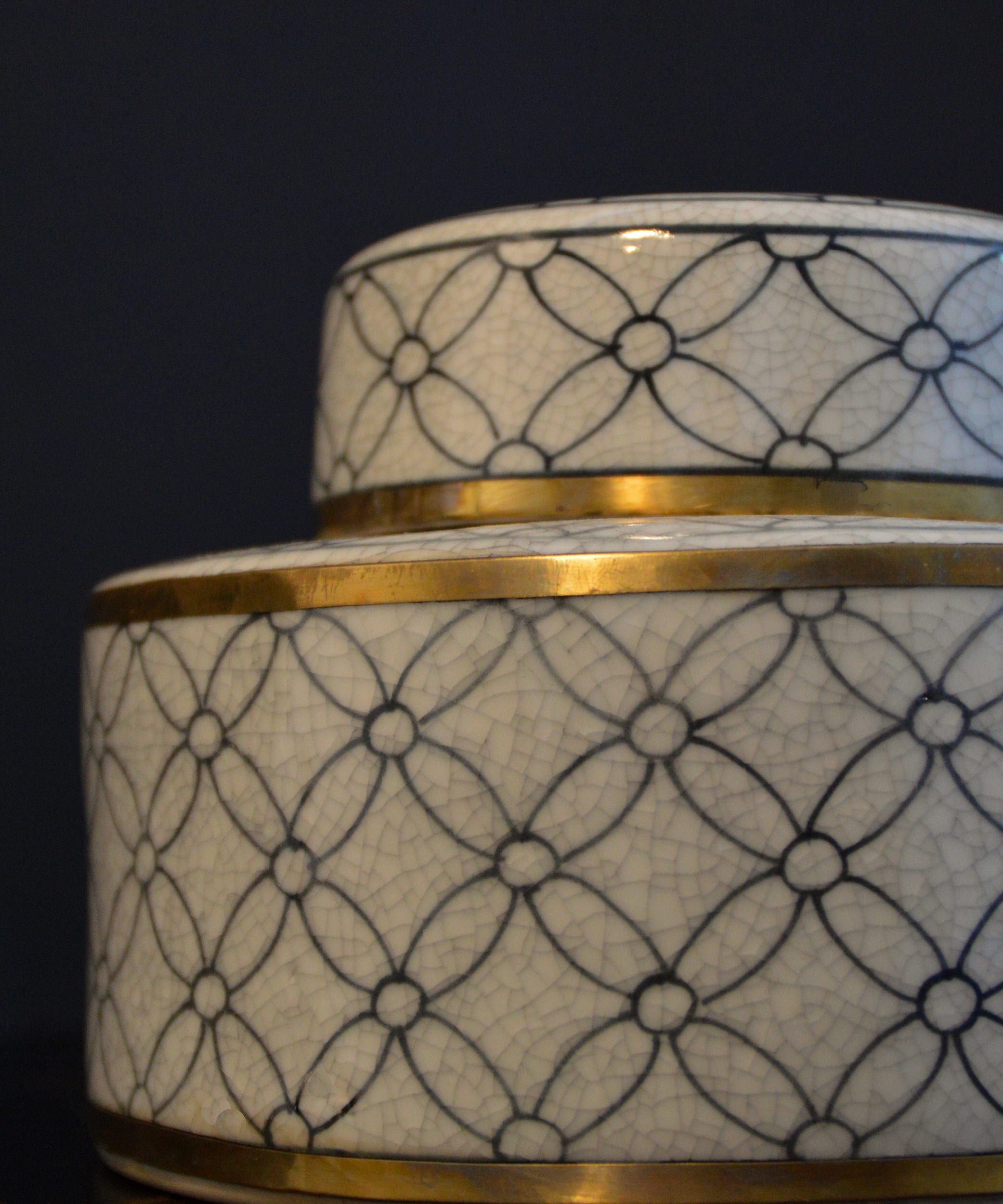 Ceramic container with geometric pattern and gold accents on a dark background