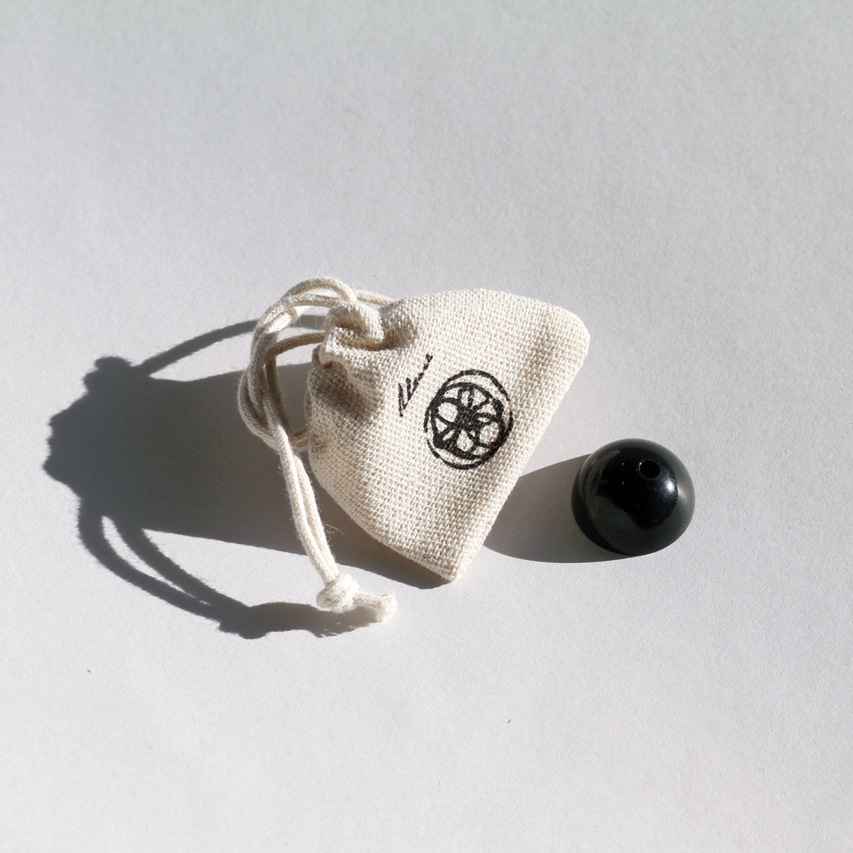 Small beige drawstring bag with a black symbol on a light gray background
