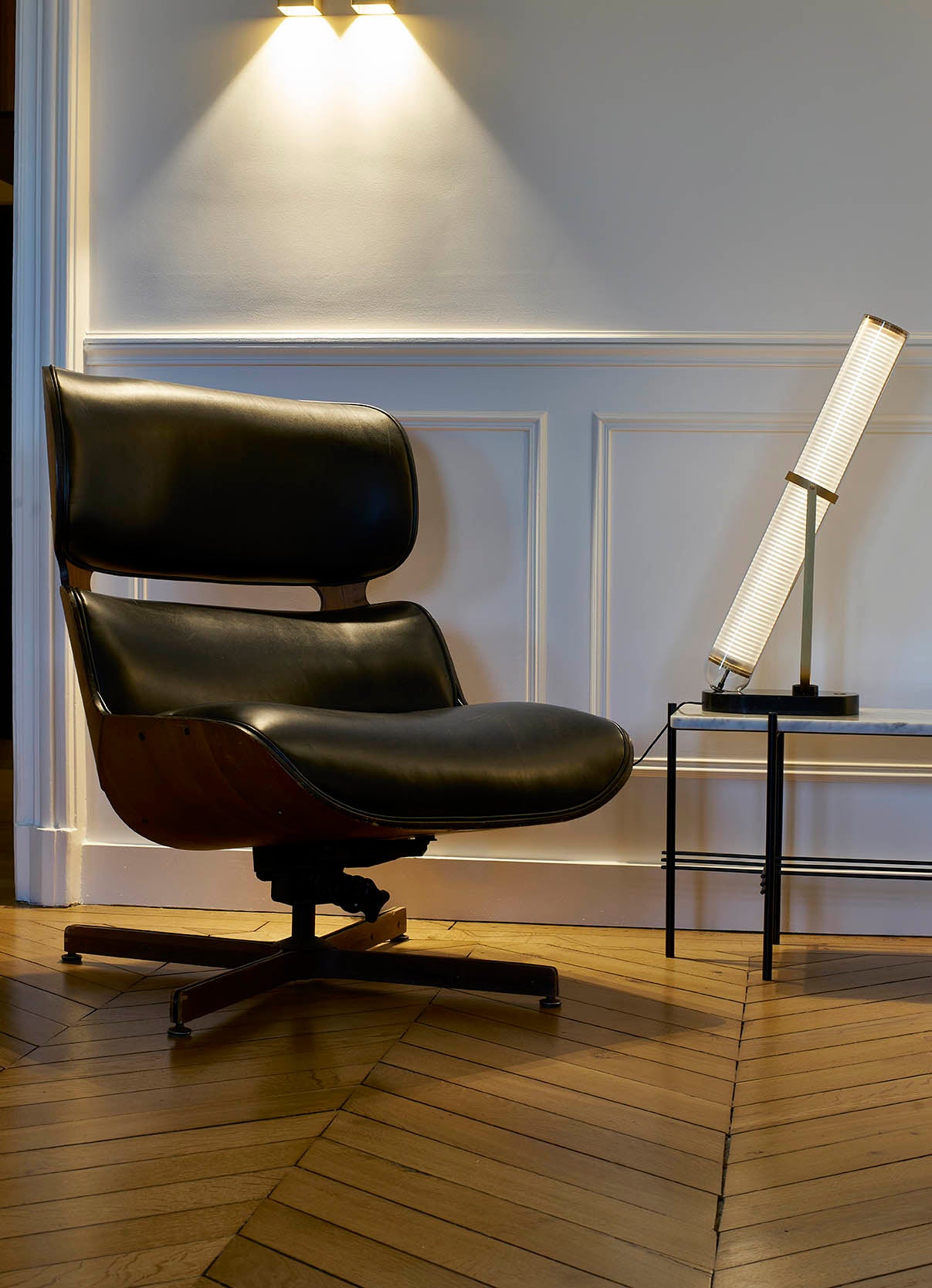 Black leather chair in a room with a lamp on a side table.