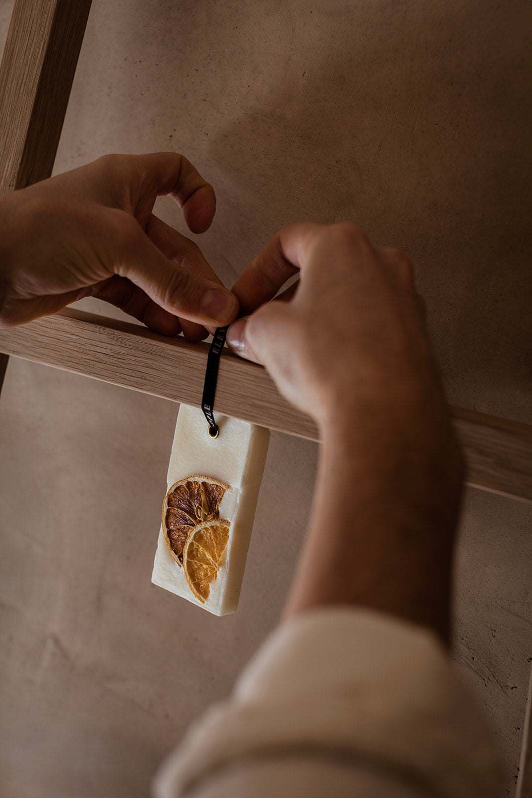 Person attaching a dried orange slice to a wooden board