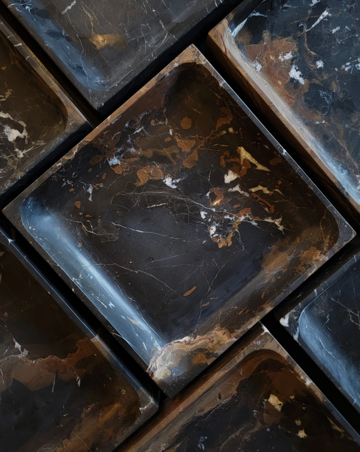 Close-up of dark, marbled stone tiles with visible cracks and imperfections.