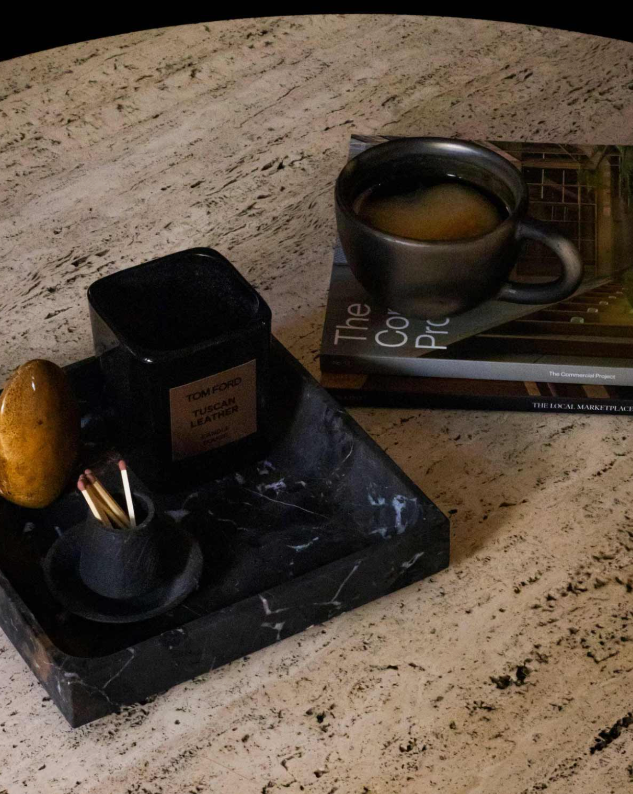 Candle holder with a candle and a book titled 'The Coffee Pro' on a marble surface