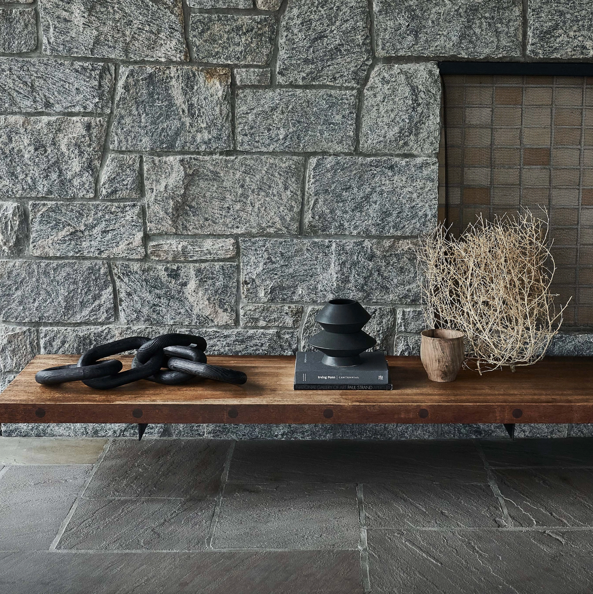 Wooden bench with decorative items against a stone wall.