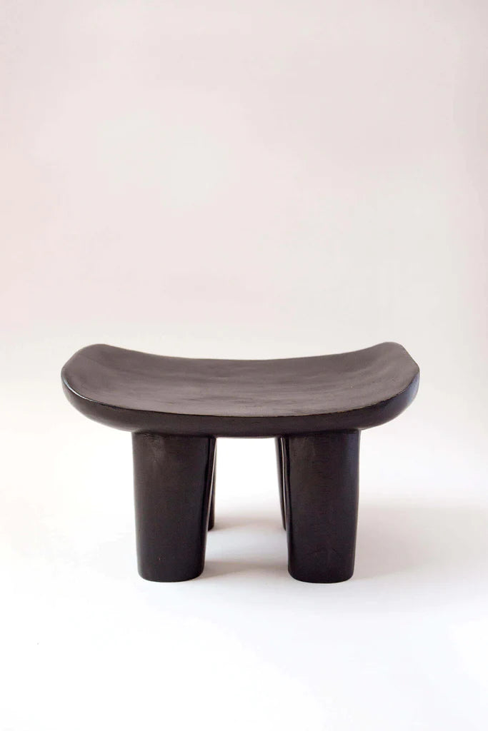 Wooden stool with curved seat and three-legged design on a white background