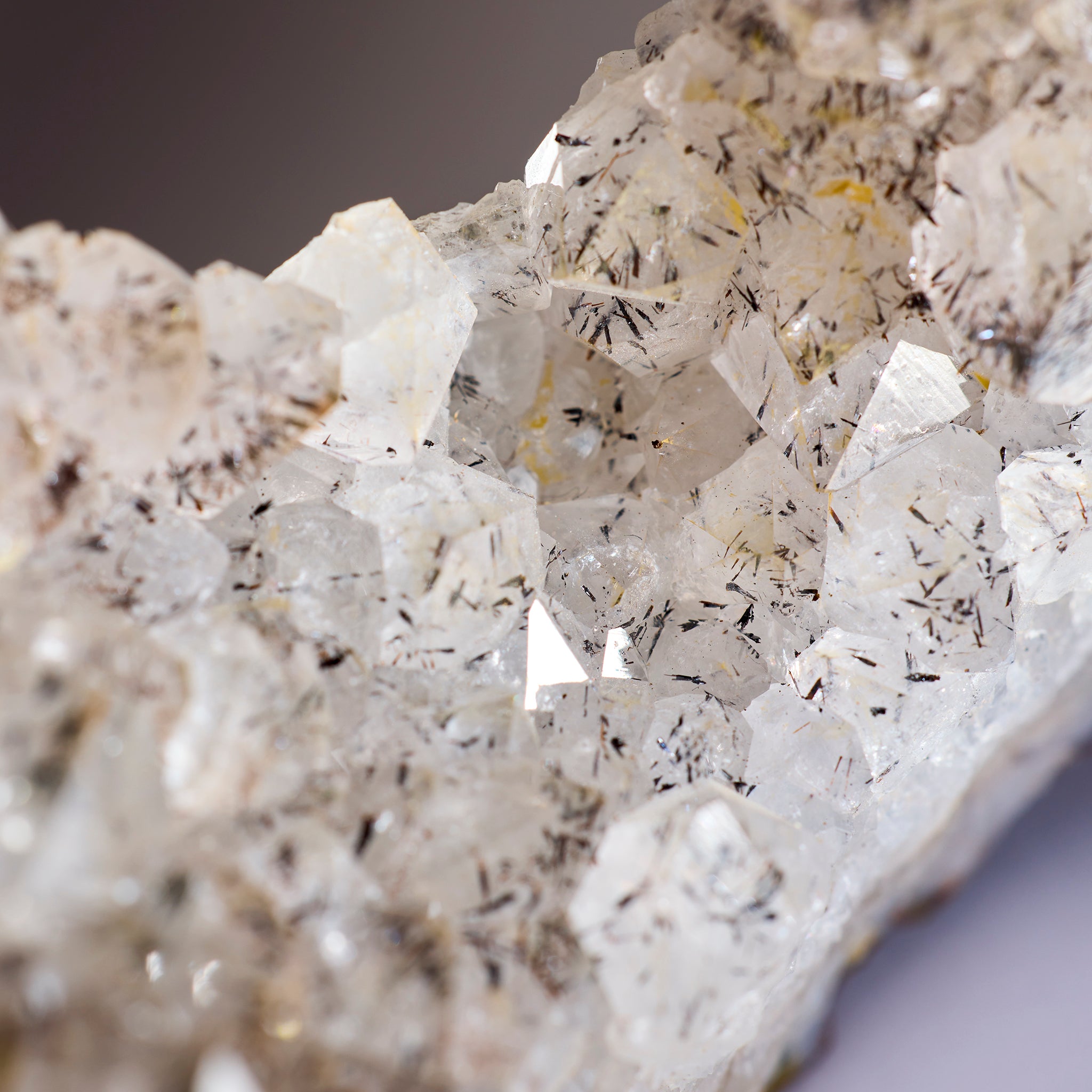 Close-up of a crystal formation with visible minerals on a gray background