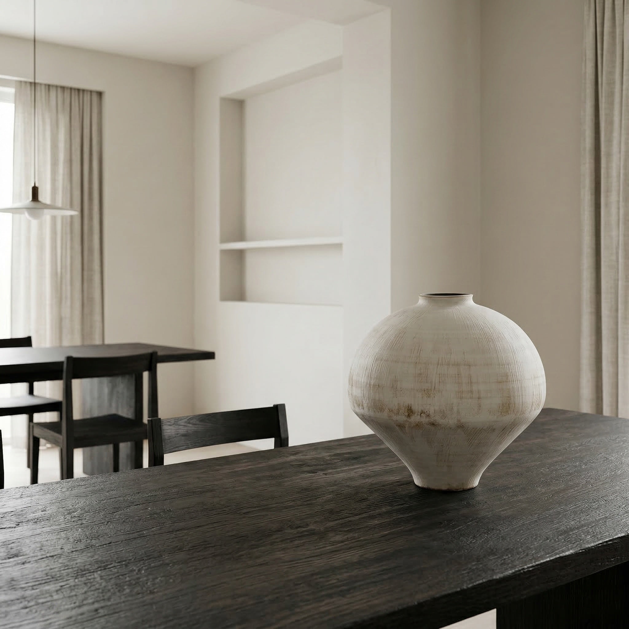White textured vase on a dark wooden table in a minimalistic room.
