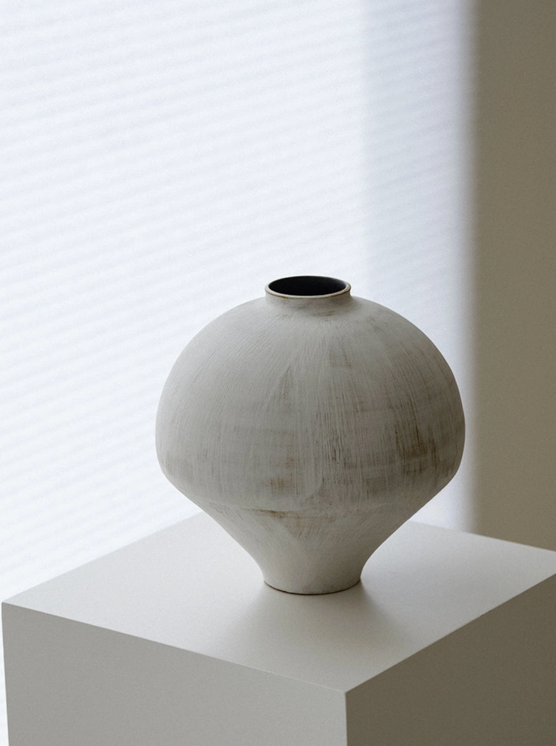 white and brown vase on white pedestal