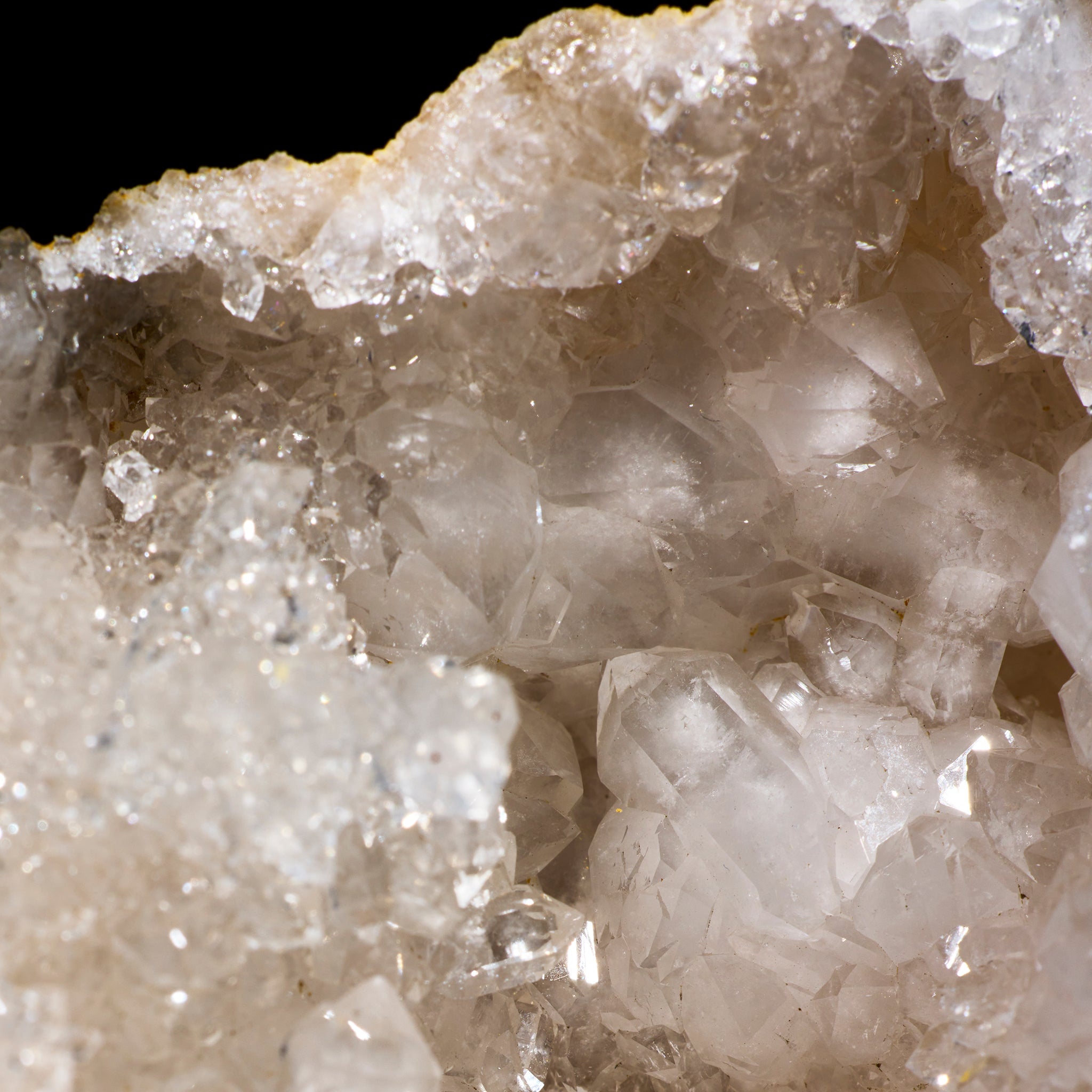 Close-up of a crystal formation with clear and beige crystals on a black background