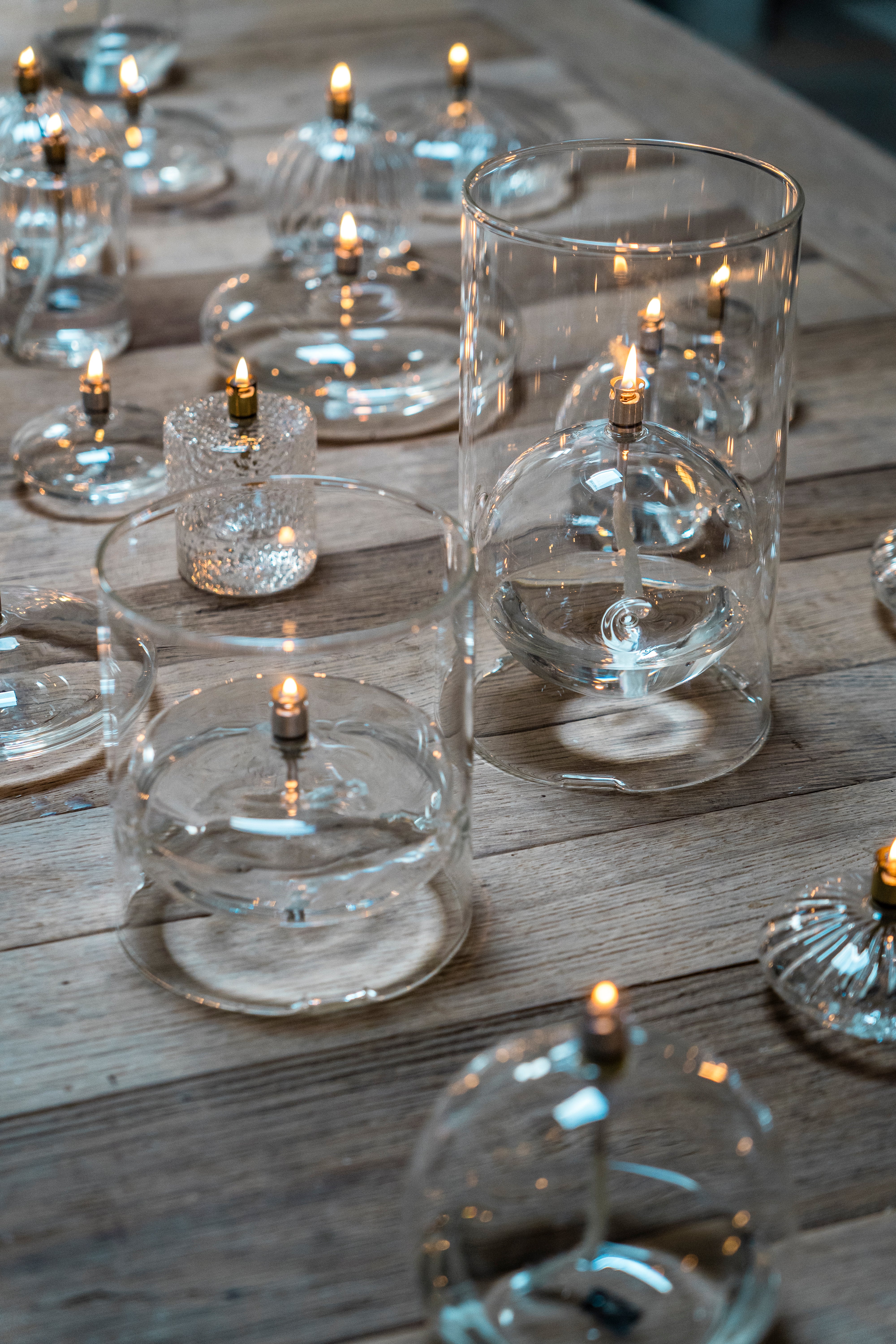 Clear glass candle holders with lit candles on a wooden surface