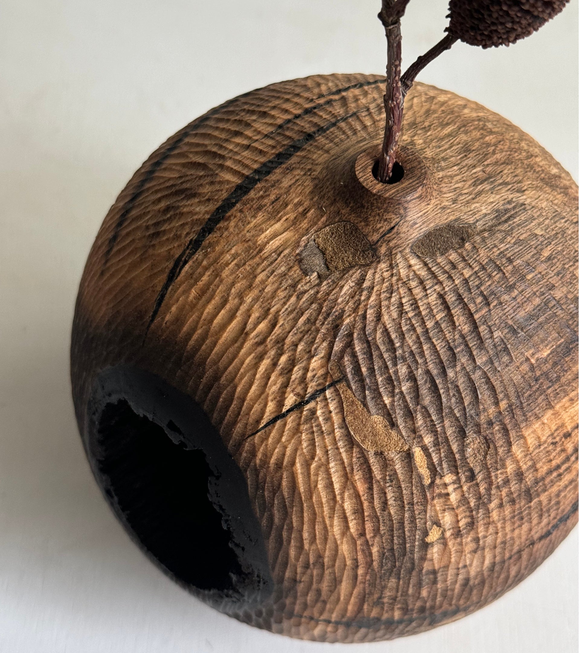 Wooden apple-shaped object with a stem on a white background
