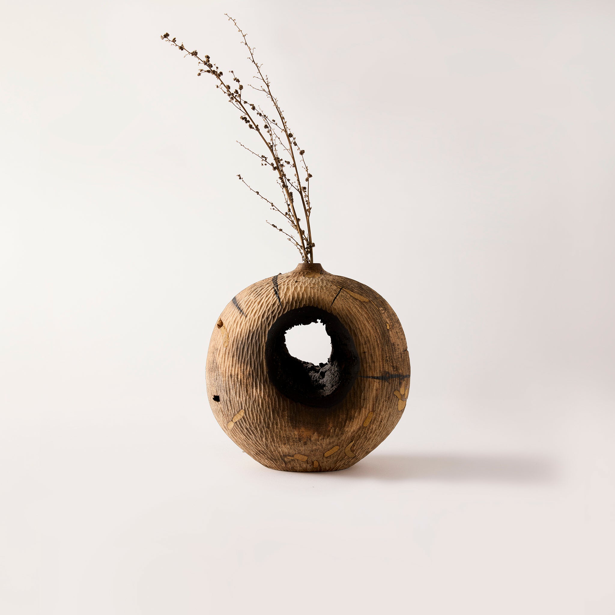 Wooden vase with a natural finish and a small plant on a light background