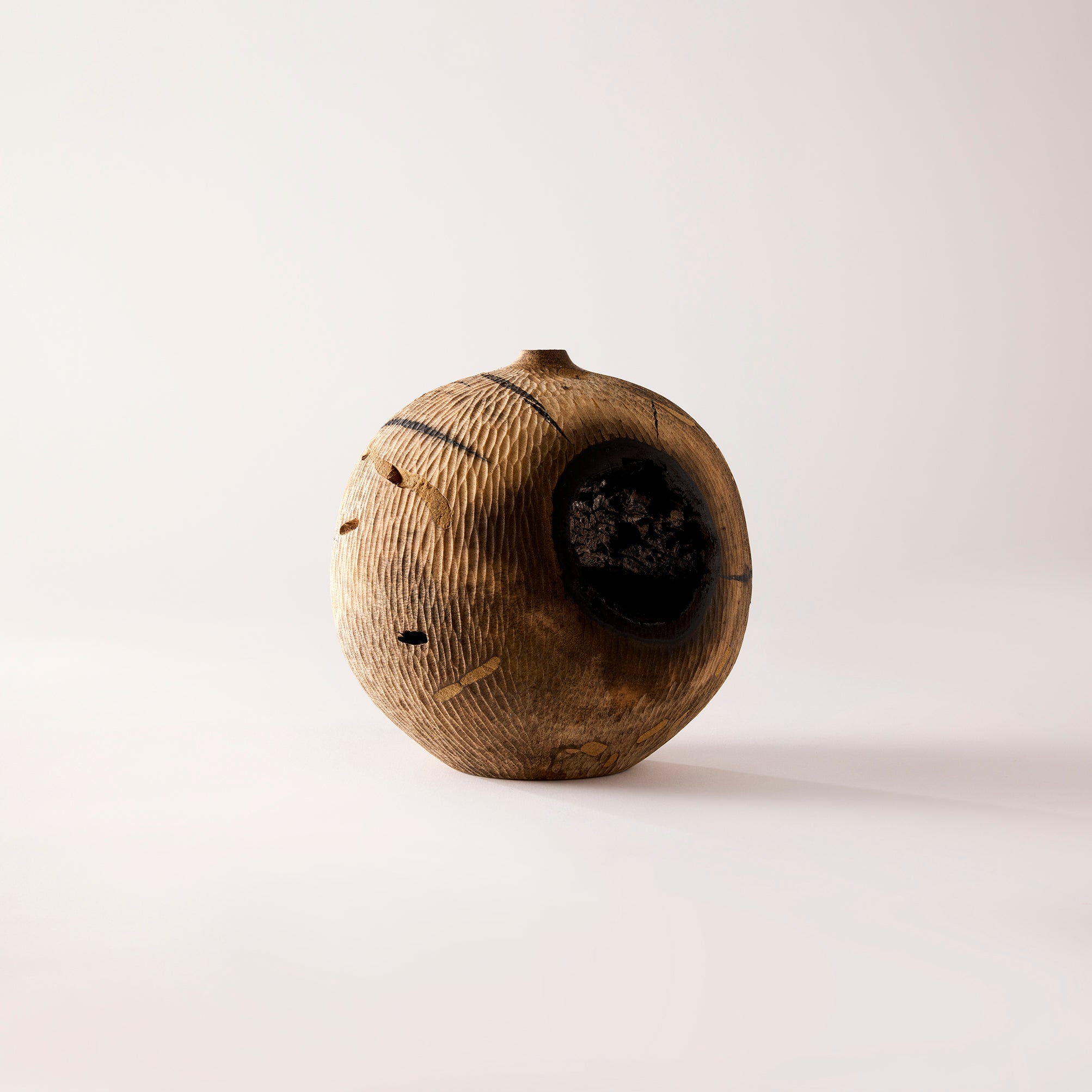Round wooden object with a textured surface on a light gray background