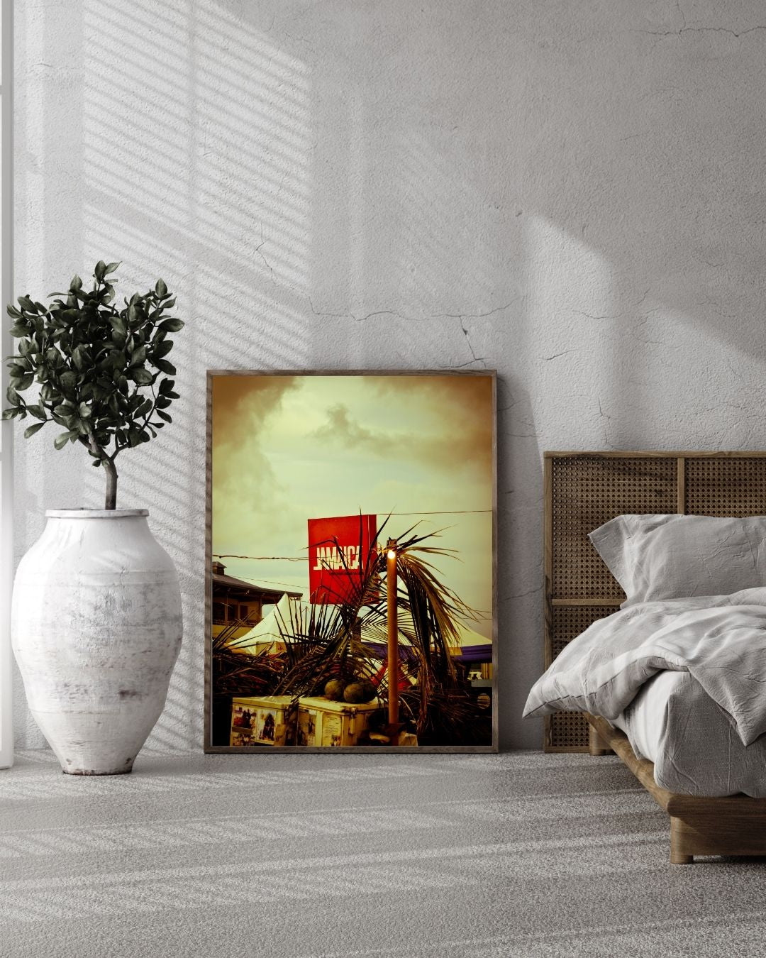 Framed artwork on a wall in a bedroom with a bed and plant.