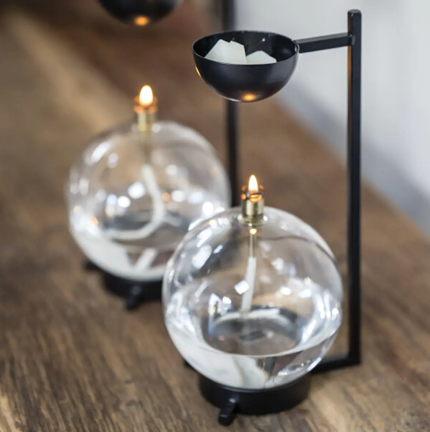 Two glass candle holders with black stands on a wooden surface.