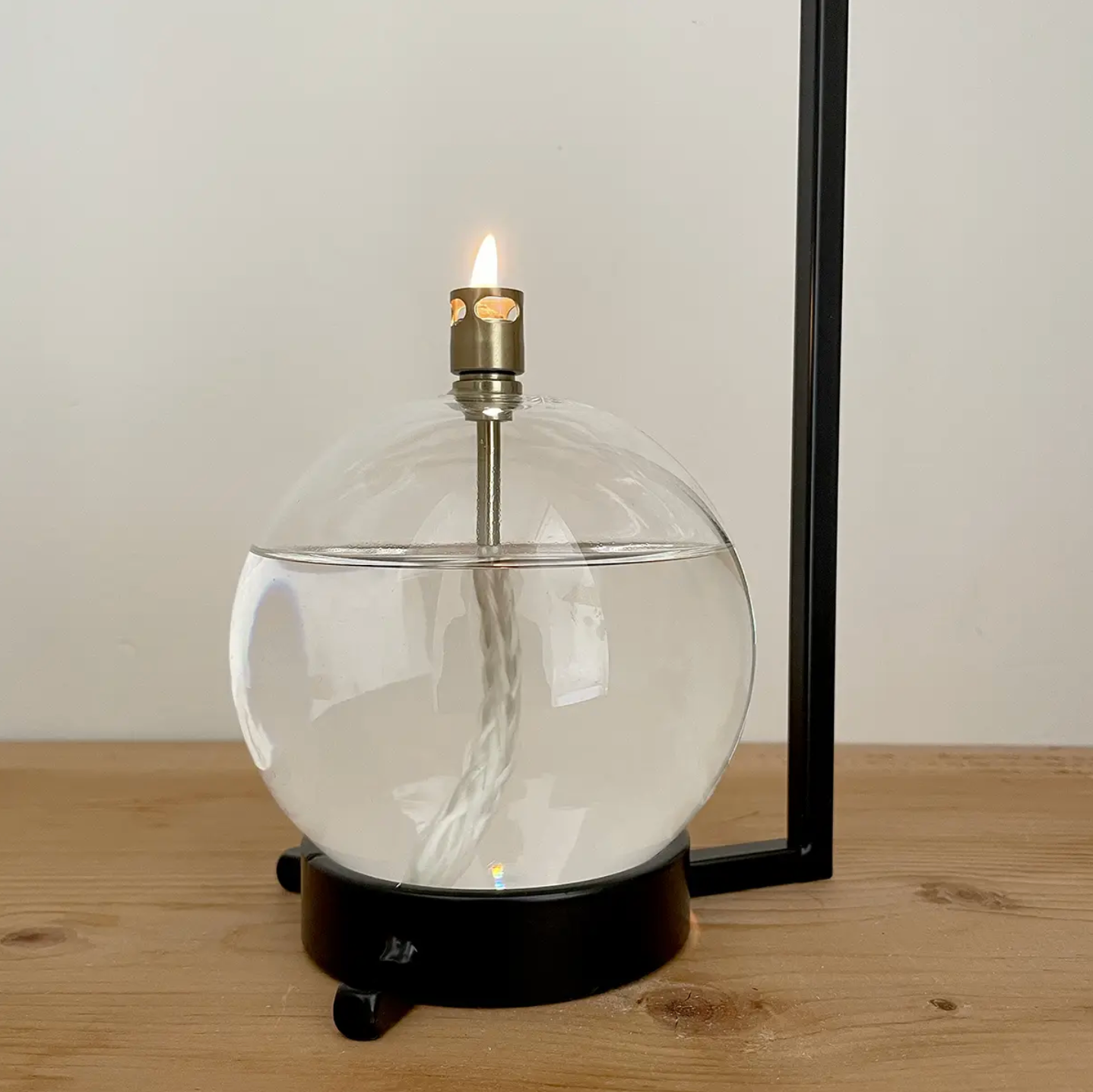 Glass table lamp with a candle inside on a wooden surface