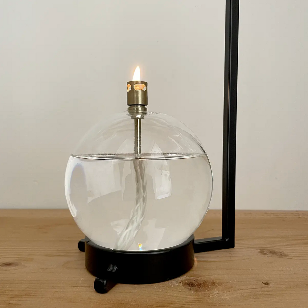 Glass table lamp with a candle inside on a wooden surface